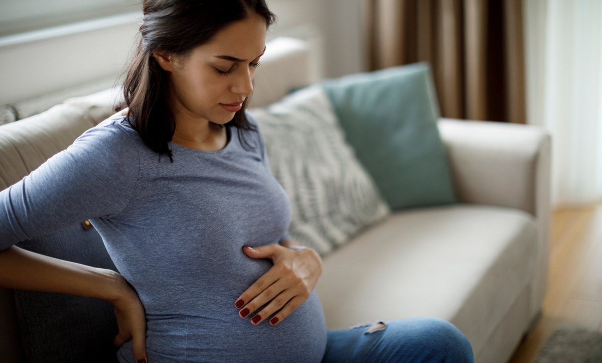 Eine schwangere Frau hält sich ihren Bauch