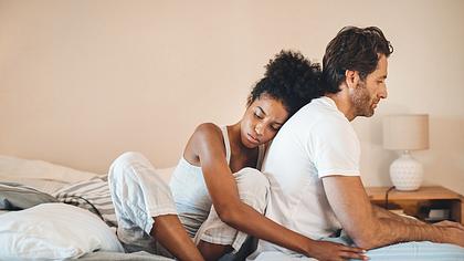 Eine Frau kuschelt sich an ihren Partner und schaut traurig - Foto: iStock/PeopleImages