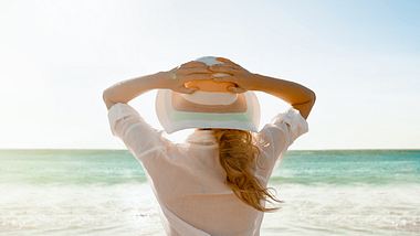 Frau von hinten, Strand, Sonnenhut - Foto: iStcok/jeffbergen