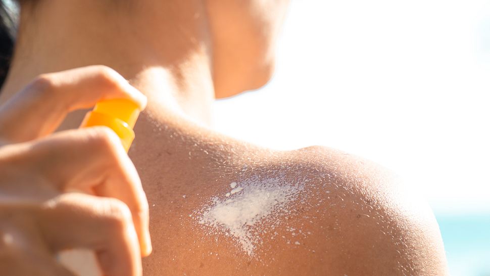 Frau sprüht Sonnencreme auf die Schulter als Sonnenschutz der Haut - Foto: iStock/solidcolours