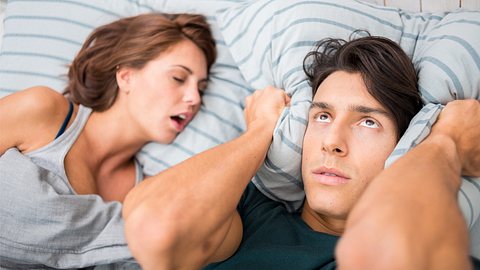 Mann hält sich Ohren zu, während die Frau schläft - Foto: istock/ilbusca