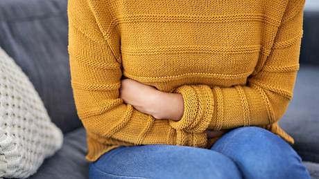 Frau mit ständigen Bauchschmerzen hält sich den Bauch - Foto: iStock/LaylaBird