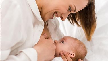 Lächelnde Frau stillt ihr Baby - Foto: istock/peopleimage_lightfieldstudios