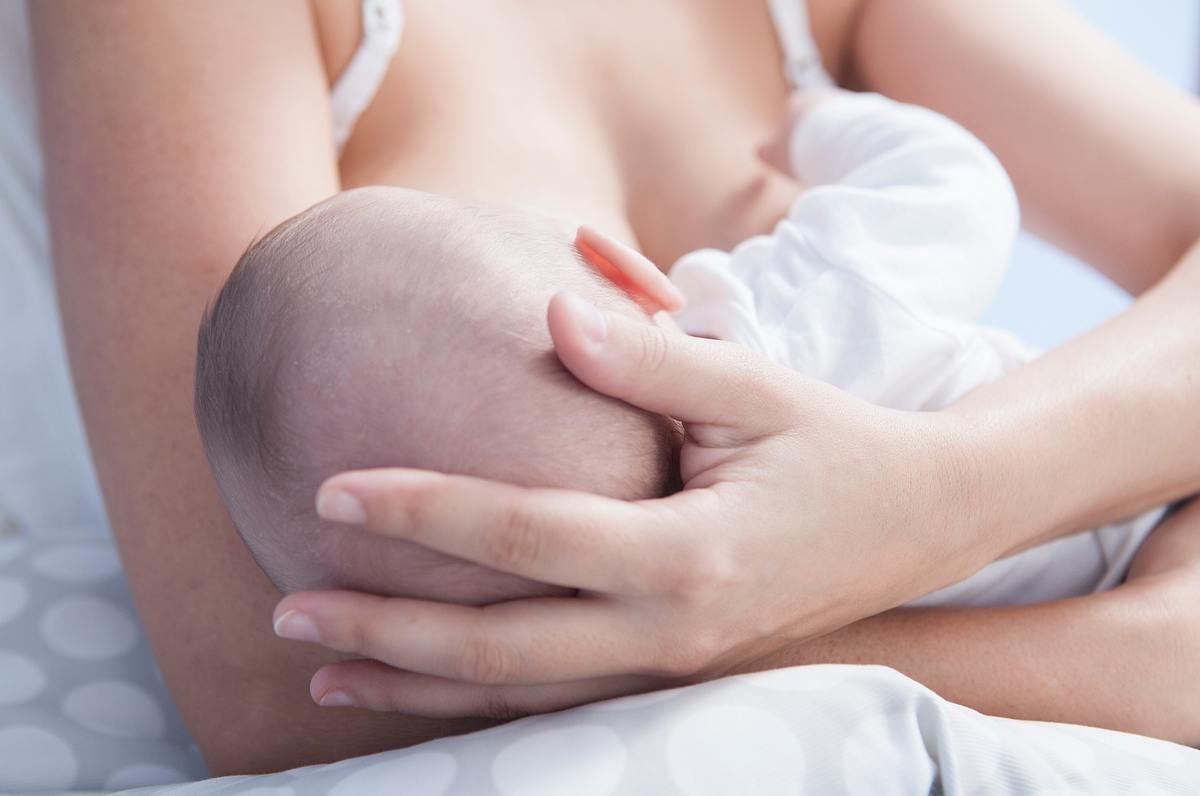 Frau legt Baby an ihre Brust zum Füttern