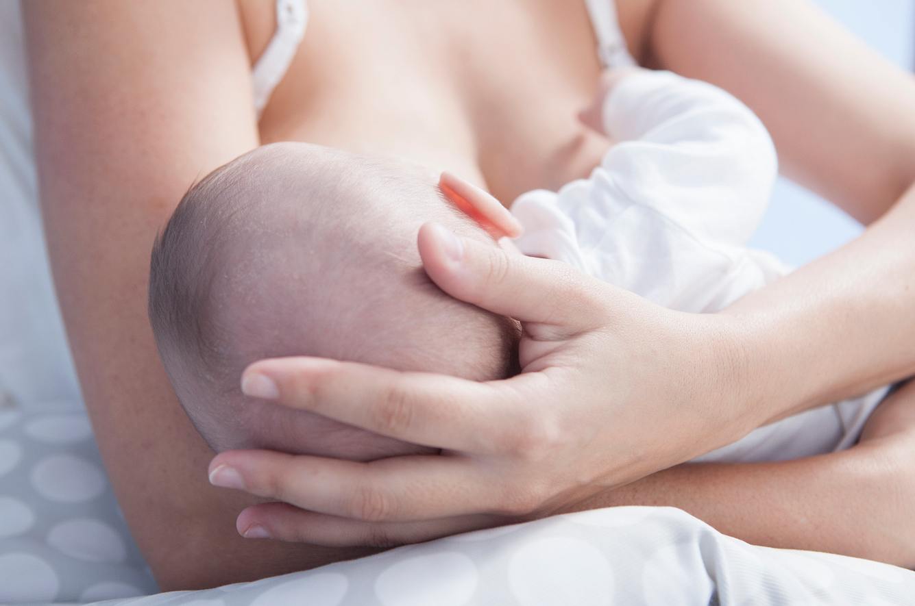 Frau legt Baby an ihre Brust zum Füttern