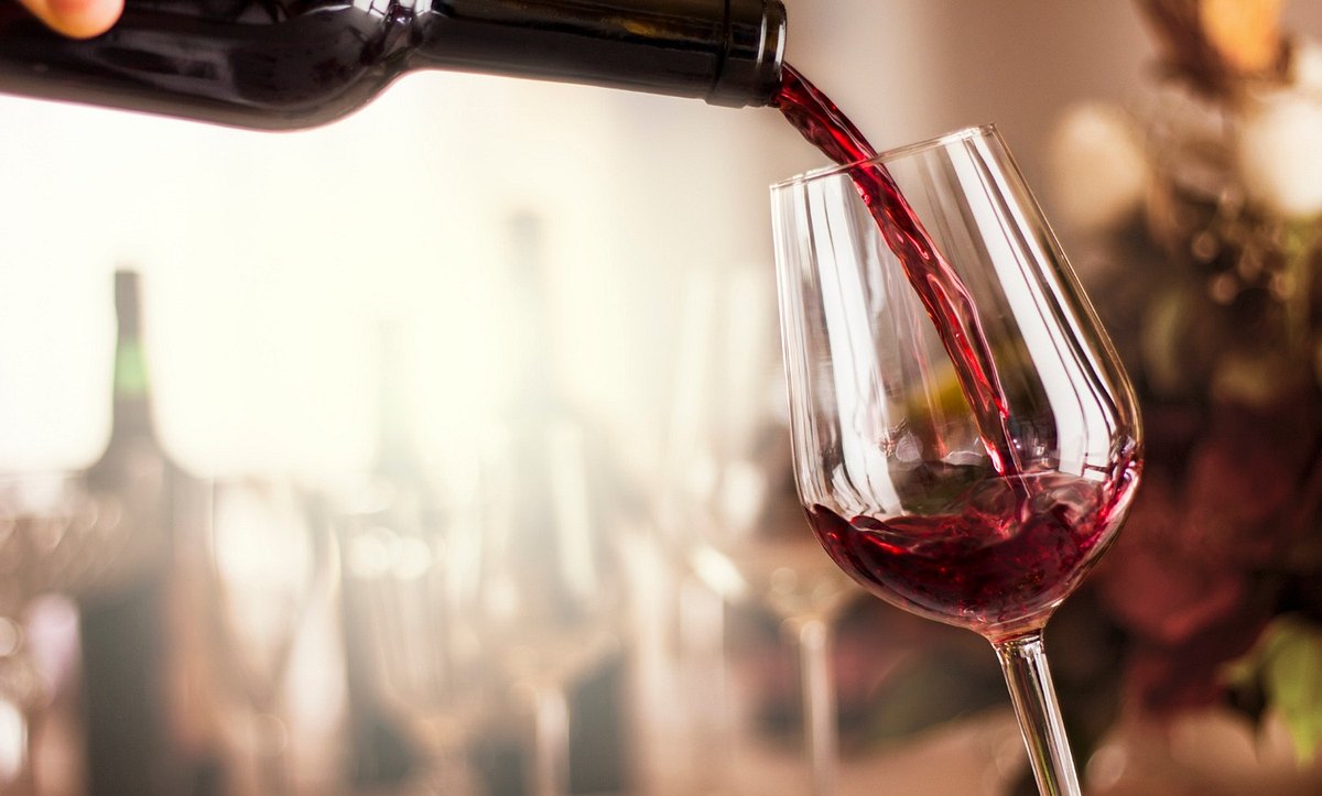 Eine Person schenkt Rotwein in ein Glas ein