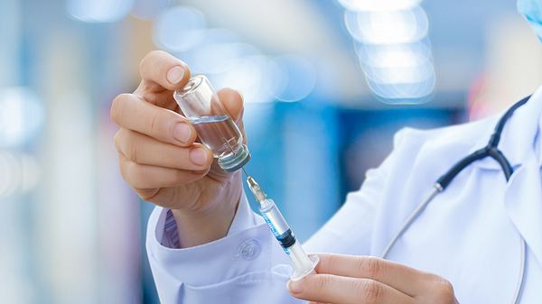 Arzt zieht Flüssigkeit in Spritze - Foto: iStock/Natali_Mis