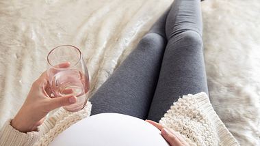 Schwangere Frau mit einem Glas Wasser - Foto: iStock/anilakkus