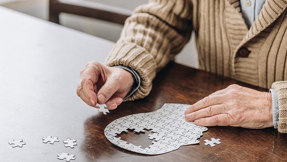 Alter Mann legt Puzzle in Kopfform - Foto: iStock/LightFieldStudios