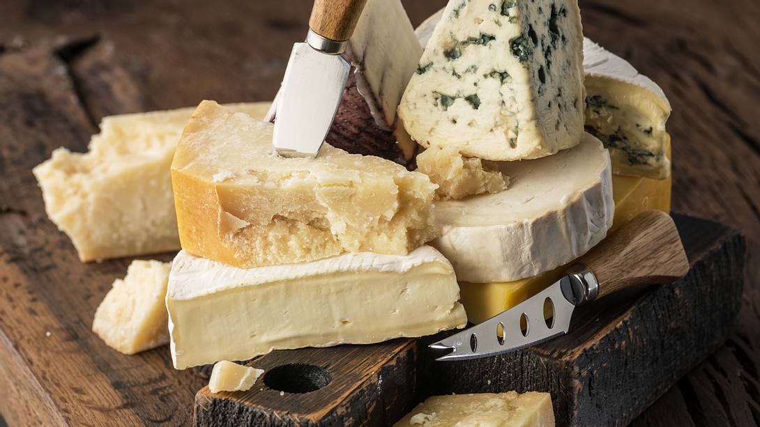 Verschiedene Käsesorten mit Käsemesser auf einem Holzuntergrund - Foto: istock/﻿ValentynVolkov