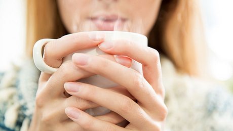 Frau trinkt heißen Kräutertee gegen trockenen Reizhusten - Foto: iStock/Sasha_Suzi