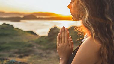 Eine Frau steht im Freien und betet - Foto: iStock/olegbreslavtsev