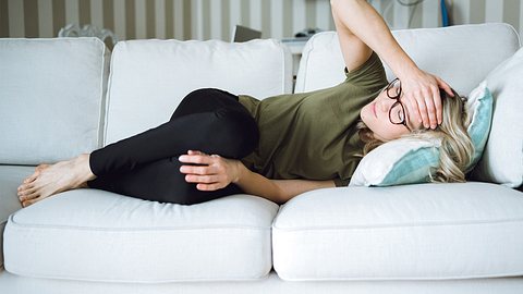 Frau mit Kopfschmerzen auf der Couch - Foto: iStock / Vertigo3d