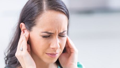 Eine Frau mit Tinnitus hält sich ihre Ohren zu - Foto: iStock_MarianVejcik
