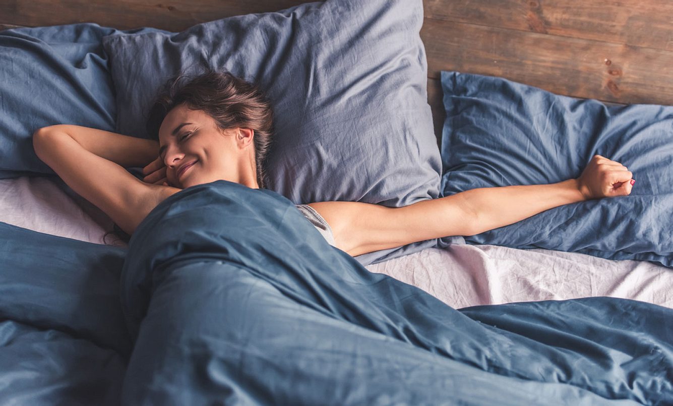 Eine Frau streckt sich im Bett