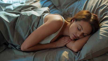 Eine Frau liegt im Bett und schläft - Foto: iStock/Geber86
