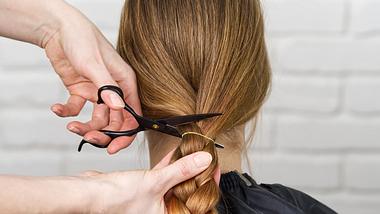 Person schneidet einer Frau die Haare ab - Foto: iStock/Ilja Enger-Tsizikov