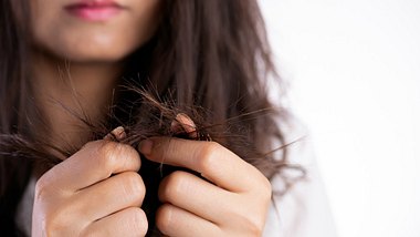 Eine Frau begutachtet ihre Haare - Foto: iStock/Tunatura