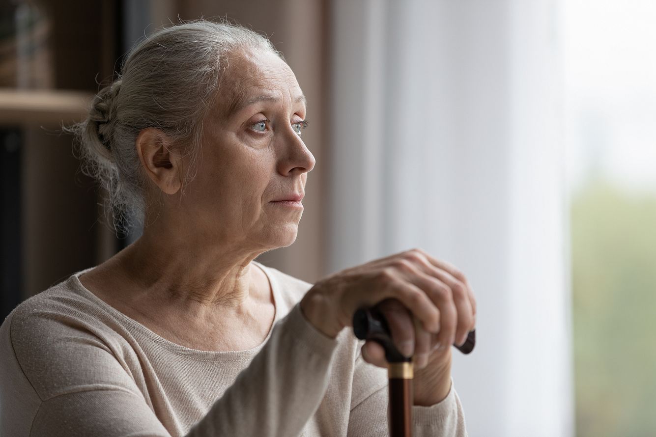 Frau mit Alzheimer Demenz schaut aus dem Fenster