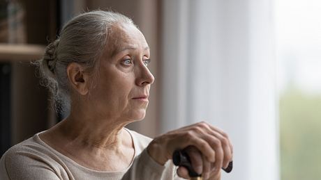 Frau mit Alzheimer Demenz schaut aus dem Fenster - Foto: iStock/fizkes