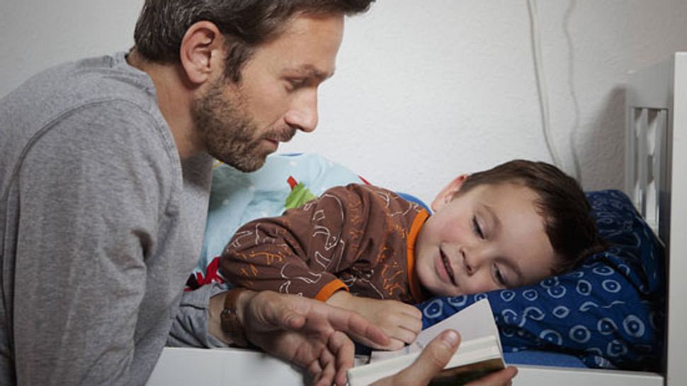 Vater und Sohn lesen Buch - Foto: imago