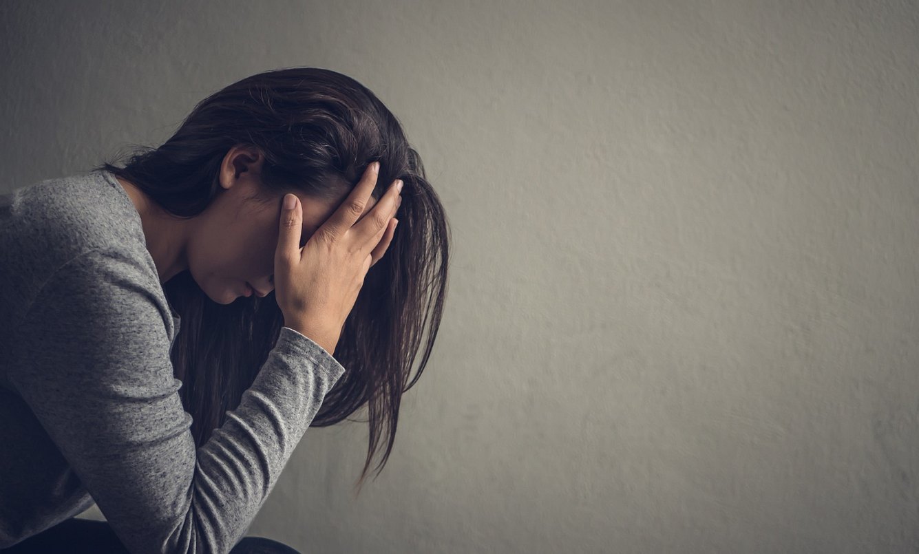 verlustangst Eine Frau sitzt auf einem Stuhl und hält sich den Kopf