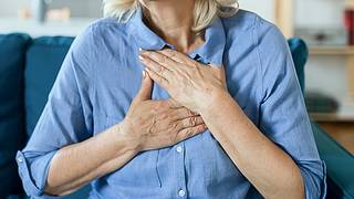 Eine Frau fasst sich an die Brust - Foto: istock/PixelsEffect