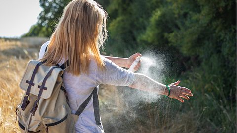 Eine Frau sprüht sich mit Mückenspray ein - Foto: iStock/Zbynek Pospisil
