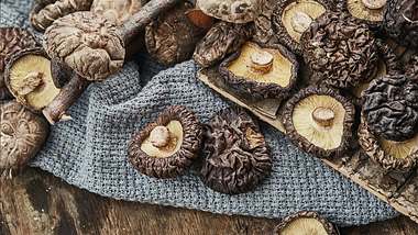Verschiedene Pilze auf einem Holztablett und einem Handtuch - Foto: istock_Easyturn