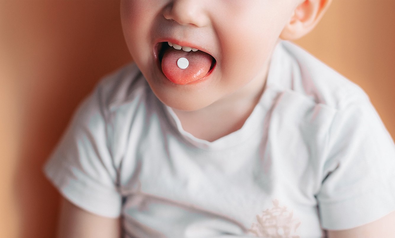 Kleinkind mit Tablette im Mund