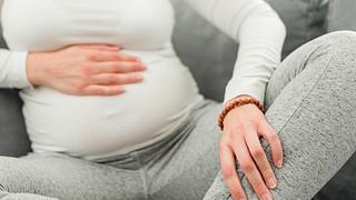 Eine schwangere Frau hält sich ihr Bein - Foto: iStock/m-gucci