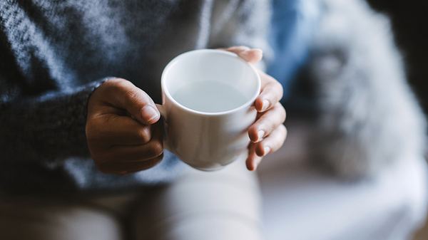 Eine Frau hält eine Tasse warmes Wasser in den Händen - Foto: iStock/kenzaza