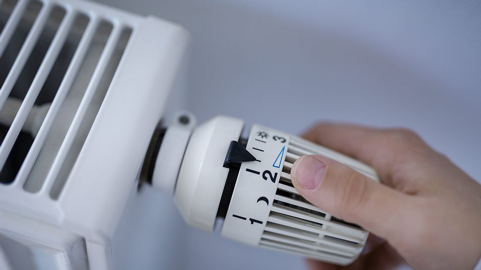 Hand am Thermostat einer Heizung - Foto: iStock/Bastian Weltjen
