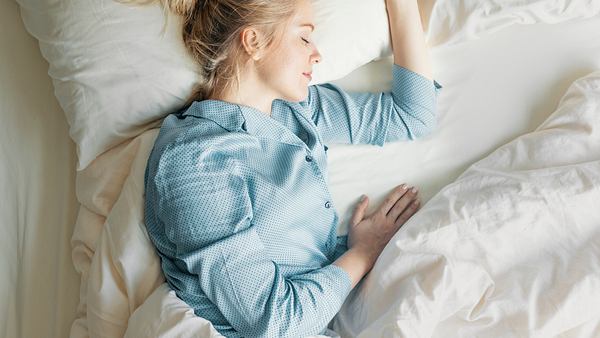 Eine Frau liegt im Bett und schläft - Foto: iStock/FreshSplash