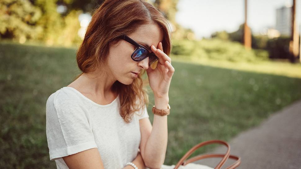 Frau mit Sommerkopfschmerzen fasst sich an den Kopf - Foto: iStock/princigall