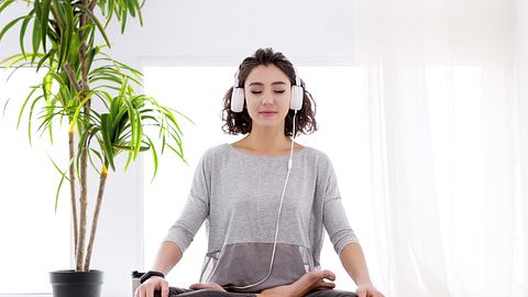 Frau macht Yoga mit Kopfhörern - Foto: iStock / monstArrr_