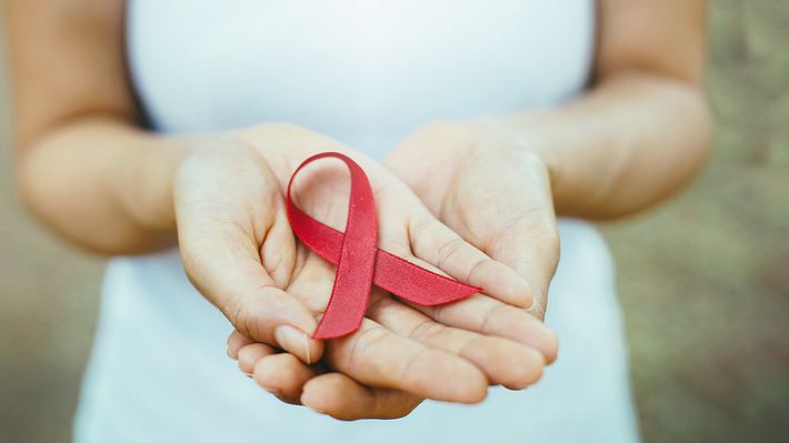 Eine Frau hält eine Aidsschleife in den Händen - Foto: iStock/4421010037