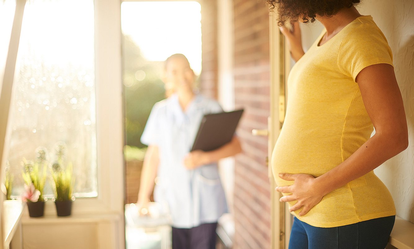 Schwangere Frau steht an der Tür