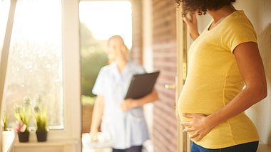 Schwangere Frau steht an der Tür - Foto: istock/sturti