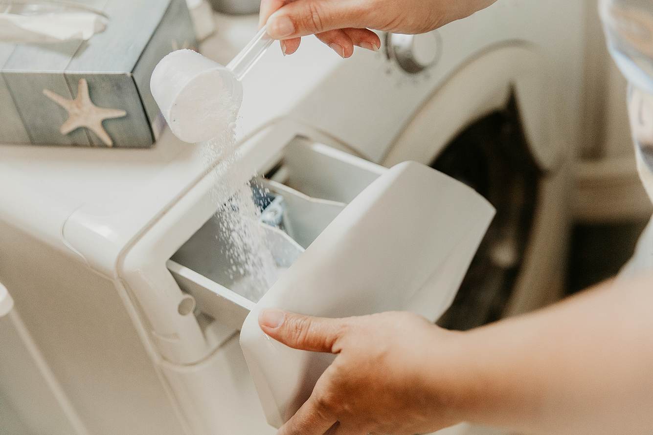Eine Frau füllt Waschpulver in eine Waschmaschine
