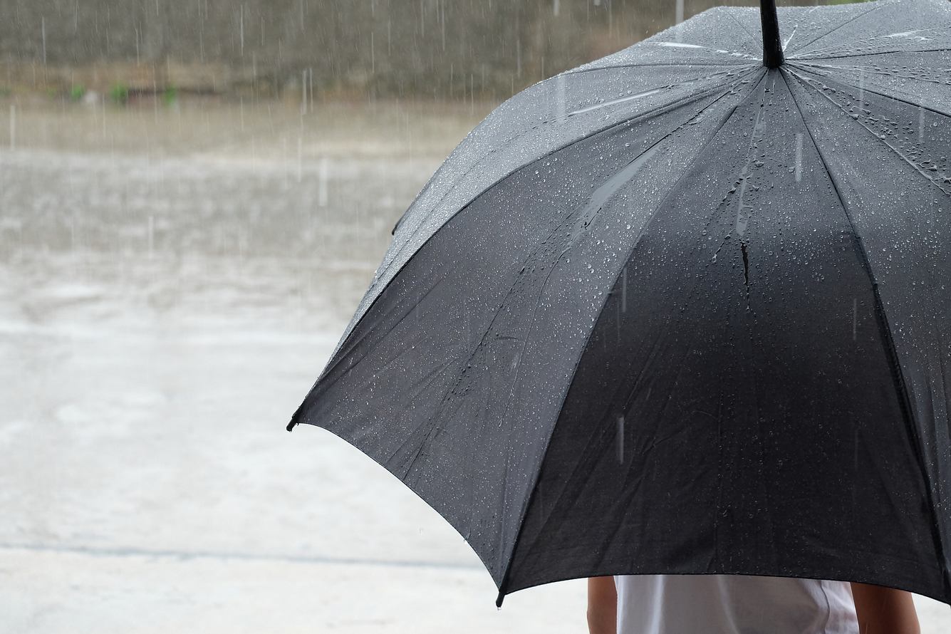 Eine Frau steht bei Regen unter einem Regenschirm