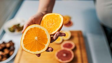 Eine Person hält eine aufgeschnittene Orange in die Kamera - Foto: iStock/ljubaphoto