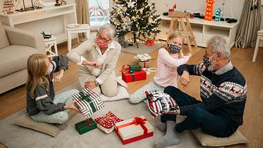 Großeltern und Kinder feiern Weihnachten mit Masken - Foto: iStock / Ivan Pantic