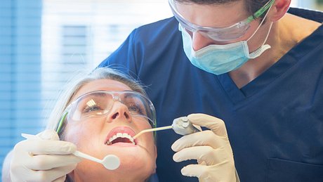 Zahnarzt schaut in den Mund von Patienten - Foto: iStock/SolStock
