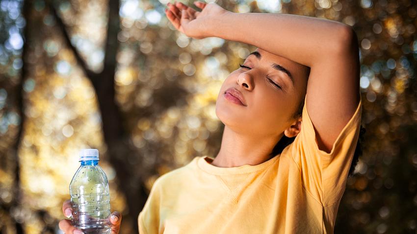 Frau mit Wasserflasche legt sich den Arm an die Stirn - Foto: iStock/Nastasic