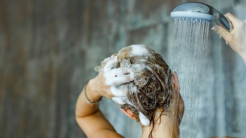 Eine Frau shampooniert unter der Dusche ihre Haare ein - Foto: iStock_skynesher