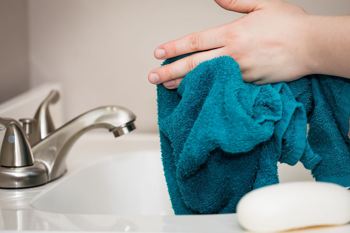 Eine Person trocknet die Hände mit einem Handtuch ab ab