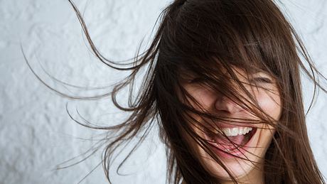 Lachende Frau mit langen Haaren - Foto: iStock/Xsandra