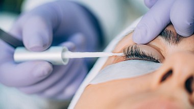 Kosmetikerin trägt Gel auf Wimpern auf - Wimpernwelle - Foto: iStock/microgen