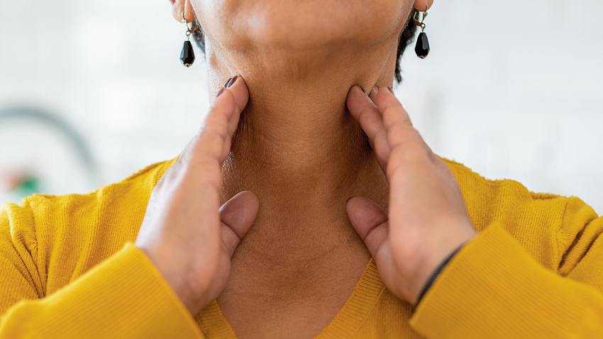 Eine Frau fasst sich mit beiden Händen seitlich an den Hals - Foto: iStock/bymuratdeniz